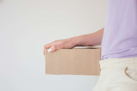Beautiful girl with a parcel in hands, delivery concept. White manicure, box with orderの写真素材