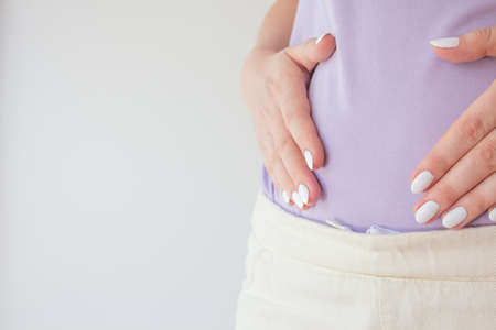 Pregnant woman in the early stages touches the belly with her hands. First and second trimester of pregnancyの写真素材