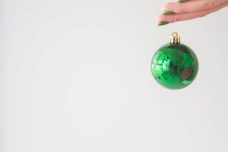 Hand holding a green christmas decoration on  whiteの写真素材