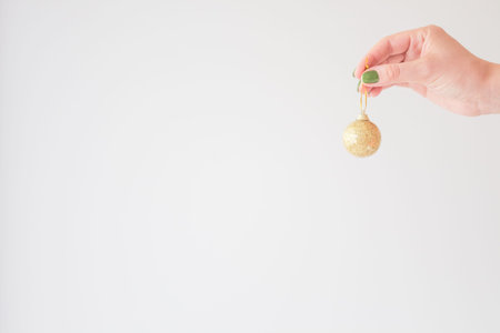 Golden christmas ball in the hand of a young woman mock up on a white background for your stylish...