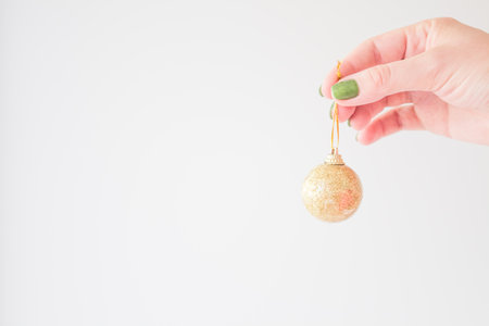 Golden christmas ball in the hand of a young woman mock up on a white background for your stylish minimalist design.の写真素材