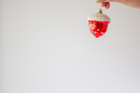 Red Christmas ball on a white background in a female hand mock up with copy space. Creative template with a bright Christmas tree toy in the snow, with snowflakes. Christmas decoration concept.の写真素材