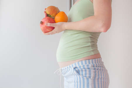 Pregnant girl eats fruits for a healthy diet and balanced nutrition. Fruit and raw foods during pregnancy. Healthy mother healthy baby.の写真素材