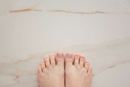 French pedicure on beautiful well-groomed female legs. Large manicure on white background done quality in a salty spa. Spa treatment.の写真素材