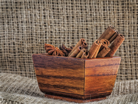 Cinnamon sticks and anise stars in a wooden trough on sackingの写真素材