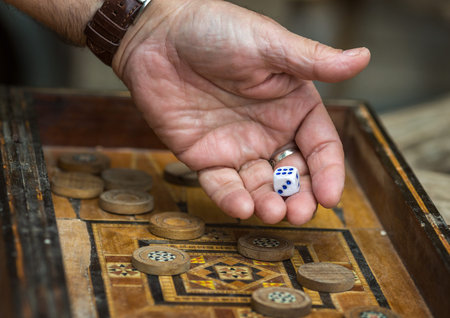 Game the antique backgammon. Man throws dice.