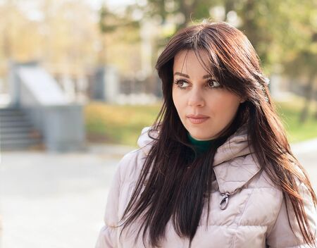 Portrait of pensive urban girl walking in city parkの写真素材