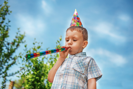 Little boy having fun and blows a party hornの写真素材