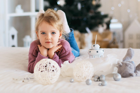 Beautiful Little girl waiting for a miracle in Christmas decorationsの写真素材