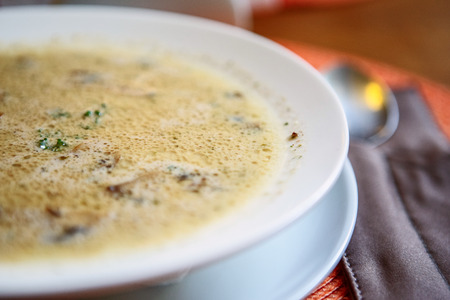Bowl of cream soup with champignon mushrooms on table in restaurantの写真素材