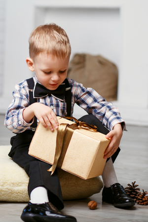 Smart Little boy opening a gift in Christmas decorations waiting for a miracleの写真素材