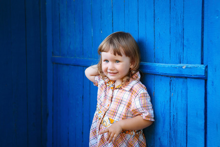 Portrait of happy joyful beautiful little girl against the old textured blue wallの写真素材
