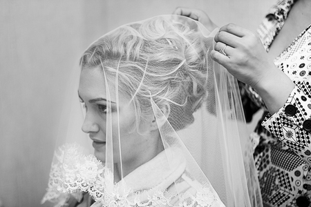 Mother helping young beautiful bride to get dressed for the wedding ceremony. Black and white photographyの写真素材