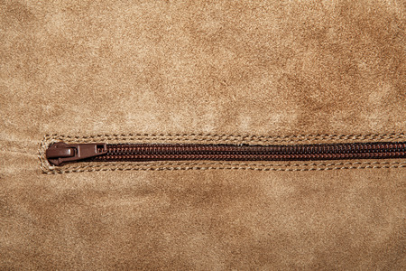 Beige suede soft leather as texture background. Old leather. Brown chamois texture. Fluffy and soft shammy-leather. Close up shammy leather texture with zipperの写真素材
