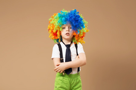 Little boy in clown wig smilling and having fun. Happy clown boy with large colorful wig. Birthday boy. Little clown boy with colorful hair. Positive emotions.の写真素材