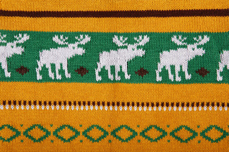 Christmas ornamental knitting with deers. knitted sweater background texture. Real knitted fabric...