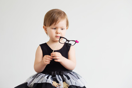 Portrait of a lovely little girl with funny photo props paper glasses against a white backgroundの写真素材