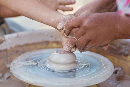 Hands of young potter, creating an earthen jar on the circle, close-upの写真素材