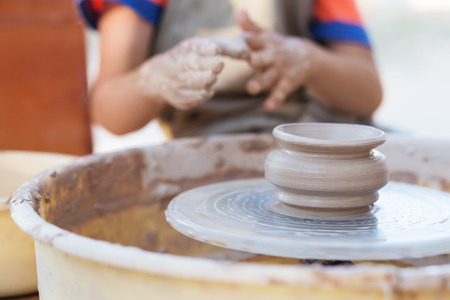 Hands of young potter, creating an earthen jar on the circle, close-upの写真素材