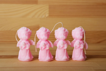 Souvenir gift candles in the shape of angels. A burning candle on wood background. Candle lit. Christmas and Easter candlesの写真素材