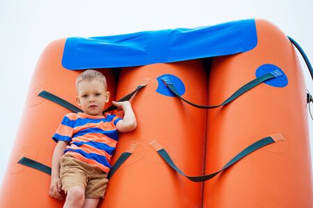 Little boy playing on an inflatable playground on the beach on a summer day.の写真素材