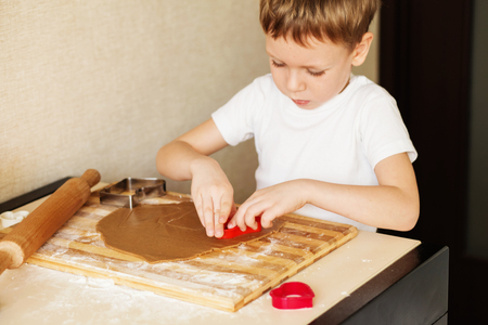 Children's hands make gingerbread. Small boy cutting cookies for Christmas. Kid Baking Cooking Cookies Fun Concept. Master class for children on baking christmas gingerbread.の写真素材