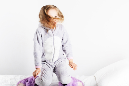 Cute little girl in pajamas jumping and having fun in bed at home. Pajama party, Day off, holiday, day of rest, free, off-timeの写真素材
