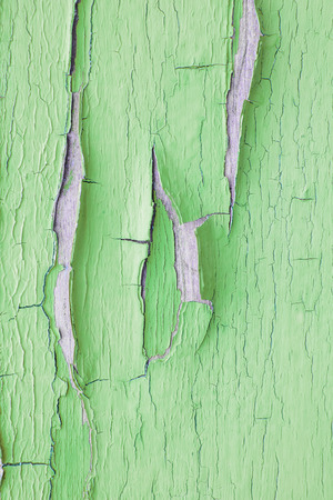 Cracking and peeling green paint on a wall. Vintage wood background with peeling paint. Old board with Irradiated paintの写真素材
