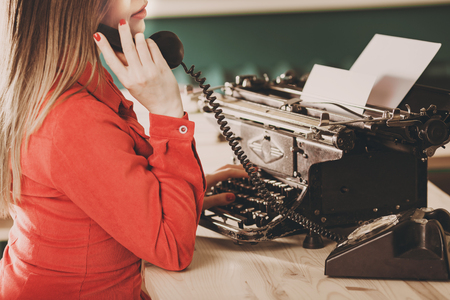 Secretary at old typewriter with telephone. Young woman using typewriter. Business concepts. Retro picture style.の写真素材