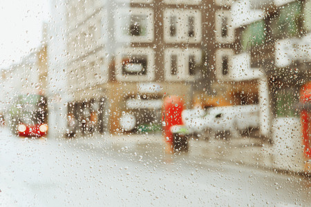 Raindrop on glass and red London bus lights blurry background. の写真素材