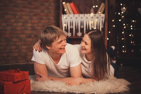 Beautiful couple in love lay on the floor at Christmas. Happy couple with christmas gifts relaxing at homeの写真素材