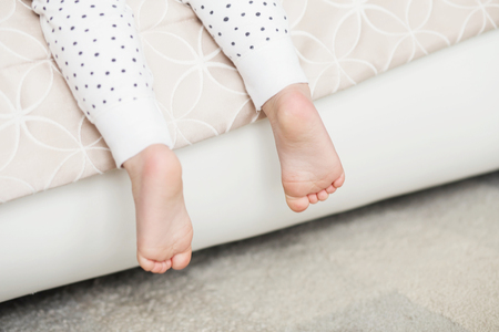 A close-up of tiny baby feet. Newborn Baby legs on the bedの写真素材