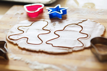 Cooking and decorating christmas gingerbread. Homemade gingerbread cookies, forms and baking ingredients. Gingerbread man and his wife. Gingerbread in the shape of a stylized human and other shapes.の写真素材