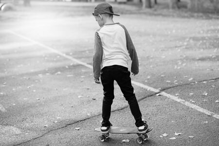 Little urban boy with a penny skateboard. Young kid riding in the park on a skateboard. City style. Urban kids. Black and white photographyの写真素材