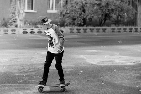 Little urban boy with a penny skateboard. Young kid riding in the park on a skateboard. City style. Urban kids. Child learns to ride a penny boardの写真素材