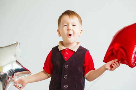 Little boy holding a star shaped balloons. Happy child playing with colorful shiny foil balloons and having funの写真素材