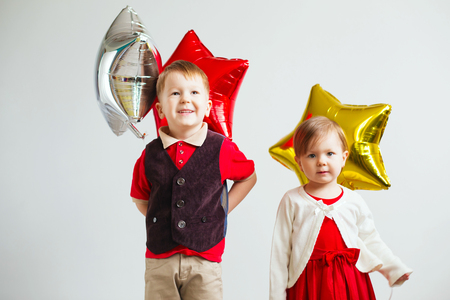 Children holding a star shaped balloons. Happy children playing with colorful shiny foil balloons against a white backgroundの写真素材