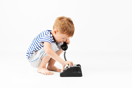 little boy with retro phone against a white backgroundの写真素材