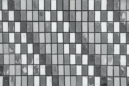 texture of old wall tiles with peeling gray paint. grey old shabby tiles background. Black and white photographyの写真素材