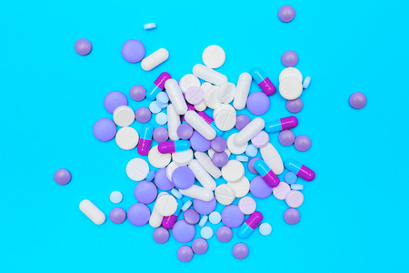drugs capsules and pills on blue background. Multicolored pills flat layの写真素材