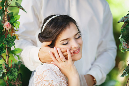 Beautiful brunette bride with bouquet outdoor. Happy bride outdoors. Beautiful bride posing in her wedding dayの写真素材