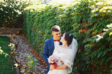 Just married loving hipster couple in wedding dress and suit in the park. Happy bride and groom walking in the beautiful garden. Romantic Married young family. Summer weddingの写真素材