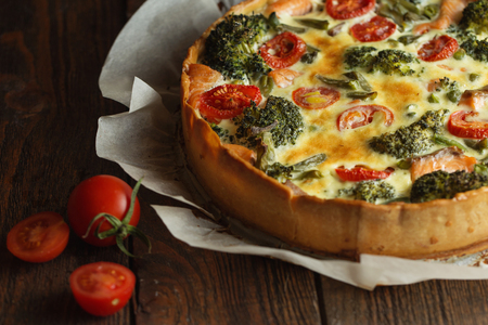 French pie Quiche or Quiche lorraine - traditional open pie with salmon, broccoli, egg, cheese, tomato.の写真素材