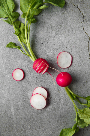 Freshly harvested, purple colorful radish on gray concrete background. Growing radish. Growing vegetables. Seasonal Cooking, food stylind. European red radishes (Raphanus sativus)の写真素材