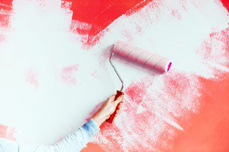 Female hand painting wall with paint roller. Close up of Decorator's hand painting wall with roller. copy spaceの写真素材