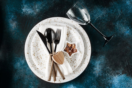 Festive table place setting. Crockery and cutlery on a dark textured background with copy space....