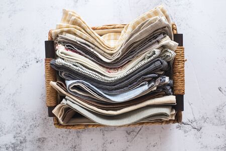 kitchen textile. stack of fabrics in different colors and textures, close-up. Kitchen towels on white background. Many fabric kitchen napkins in a wicker basket. Props for food photographyの写真素材