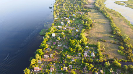 Drone fly over waving river surrounded by local village with various buildings and Wetland and marsh...