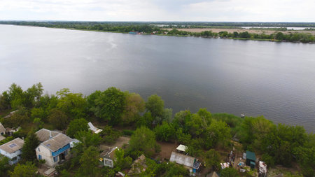 Drone fly over waving river surrounded by local village with various buildings and Wetland and marsh...