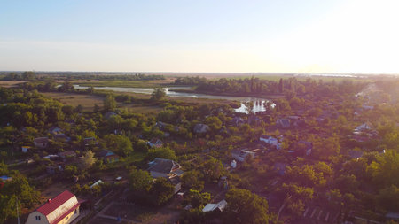 Drone fly over waving river surrounded by local village with various buildings and Wetland and marsh...